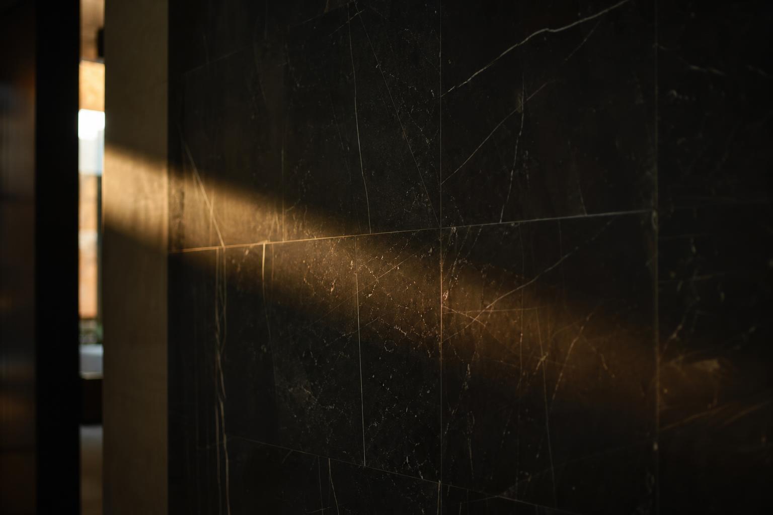 Black marble wall with a single warm line of natural light