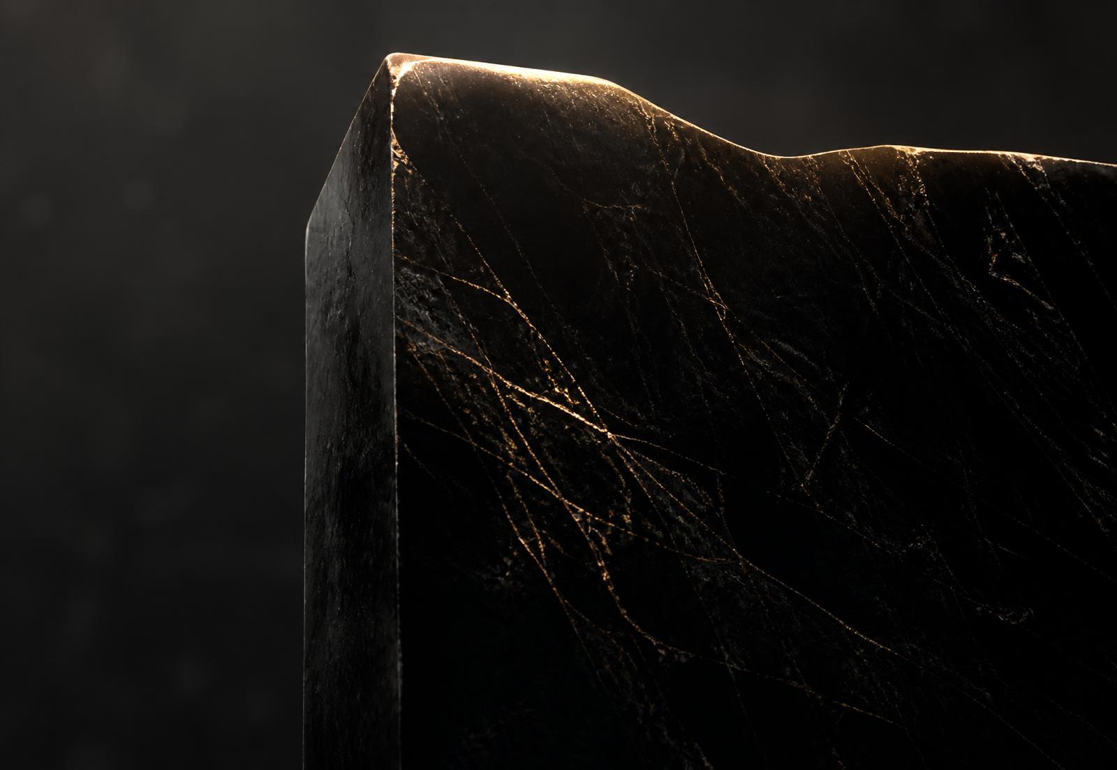 Polished obsidian monolith lit by a single line of gold light